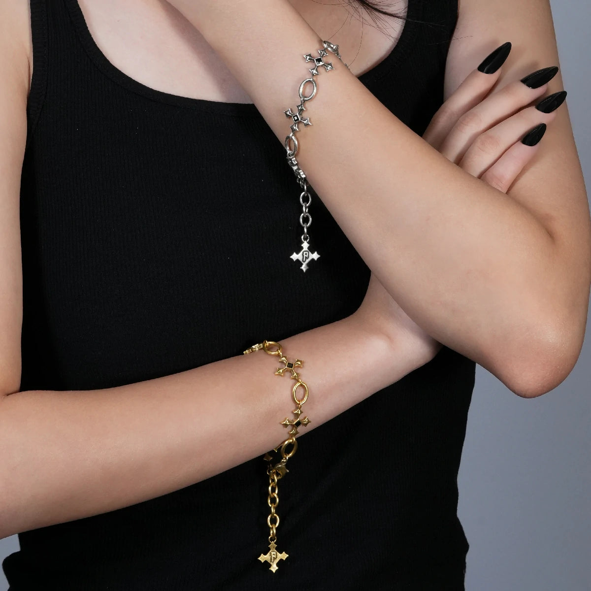 Silent Litany Bracelet in antiqued 18K gold worn on the wrist in a crossed-arm close styling shot over a black top.