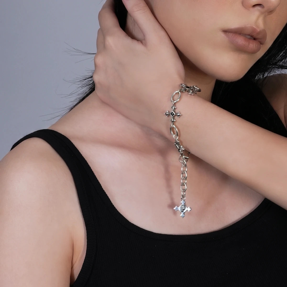 Silent Litany Bracelet in antiqued silver worn on the wrist as the model touches her neck, styled with a black top.