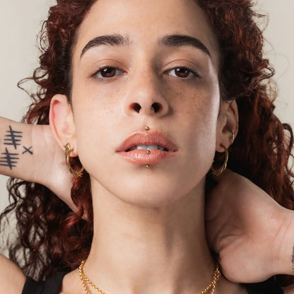 Model wearing the gold Siren Crest Earrings with a sculptural ocean-inspired half-hoop silhouette and gothic styling.