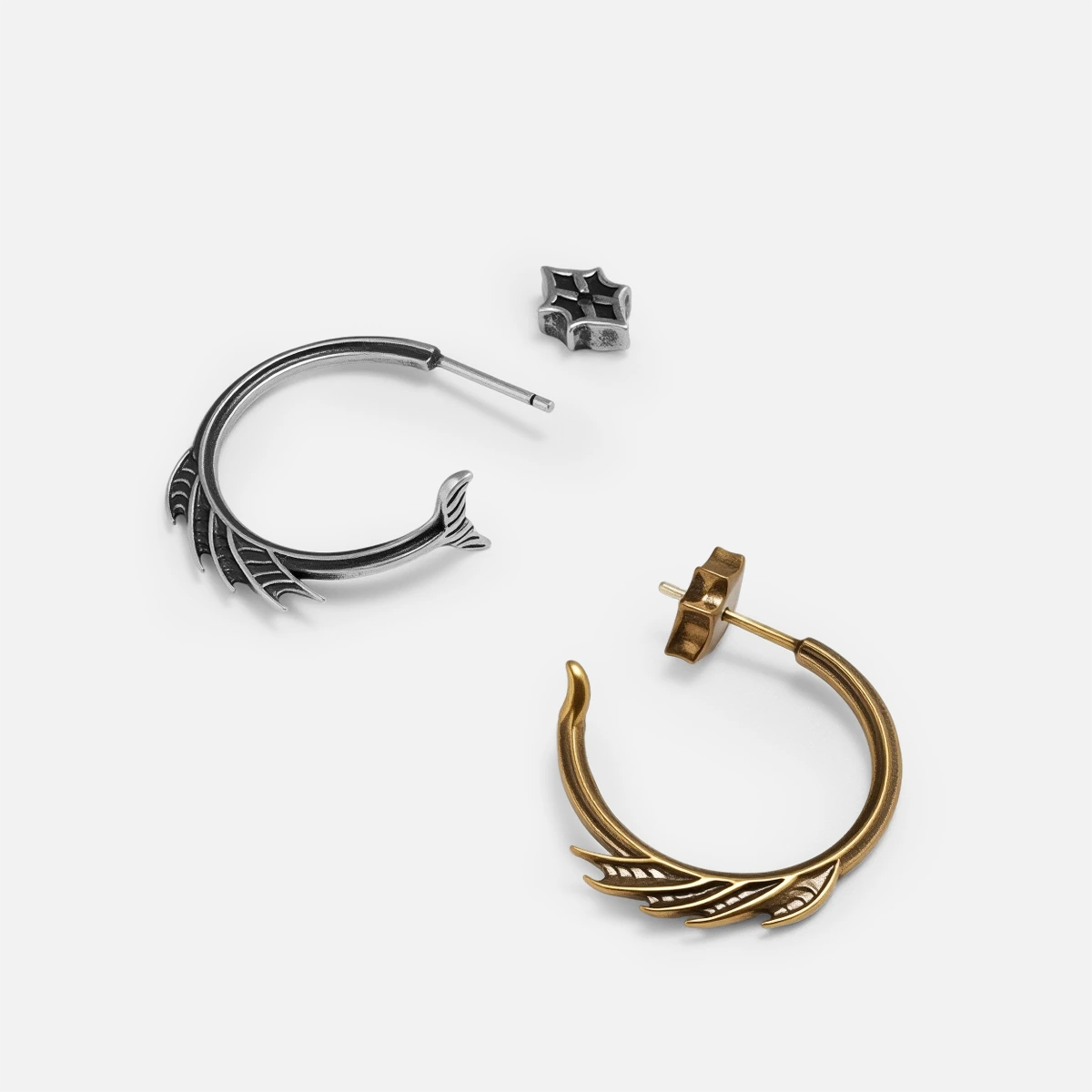 Silver and gold Siren Crest Earrings shown together, featuring fin-like ridges, curved half-hoop forms, and post-back closures.