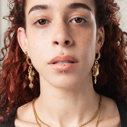 Model wearing the gold Siren's Dirge Earrings with layered jewelry, highlighting the long siren charm drop and oceanic gothic mood.