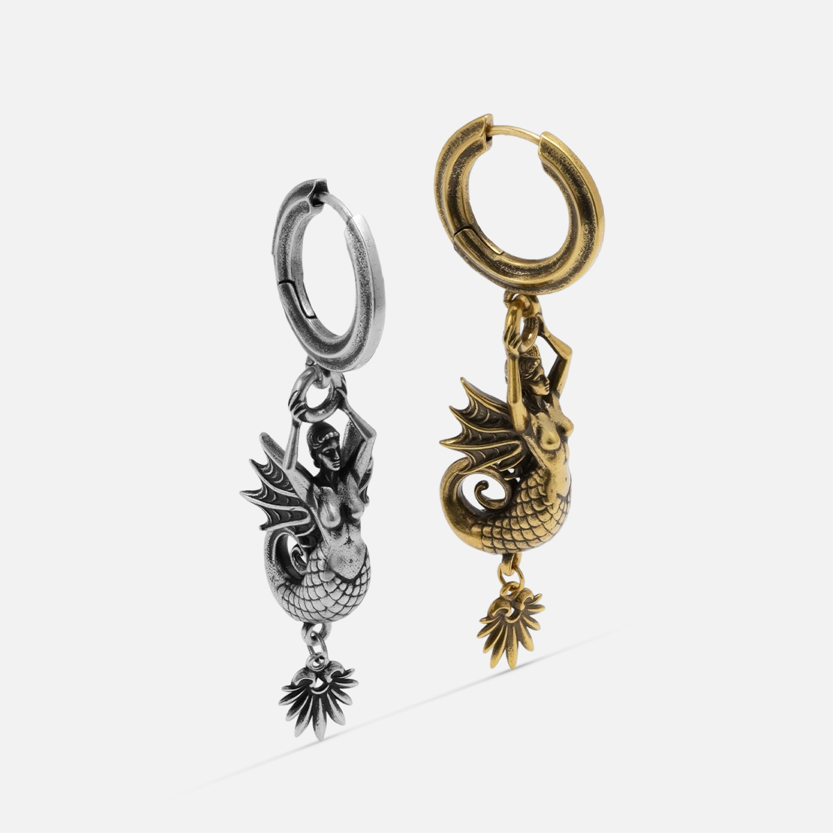 Silver and gold Siren's Dirge Earrings shown together, featuring sculpted siren figures, hoop closures, and dangling charm details.