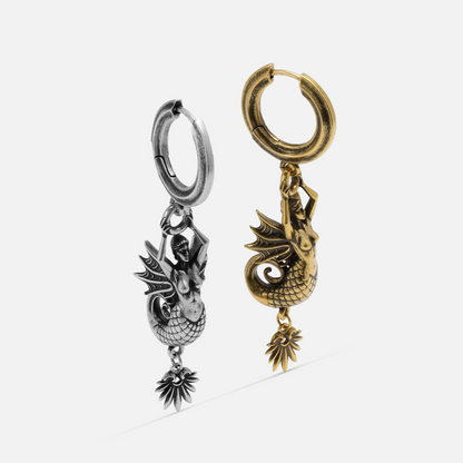 Silver and gold Siren's Dirge Earrings shown together, featuring sculpted siren figures, hoop closures, and dangling charm details.