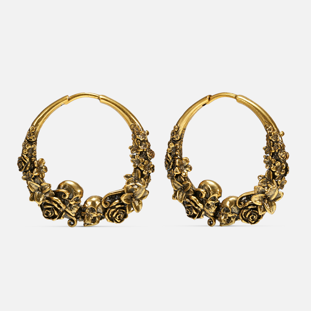 Pair of antique gold-tone hoop earrings with skull and rose blossom detailing, front view on white background