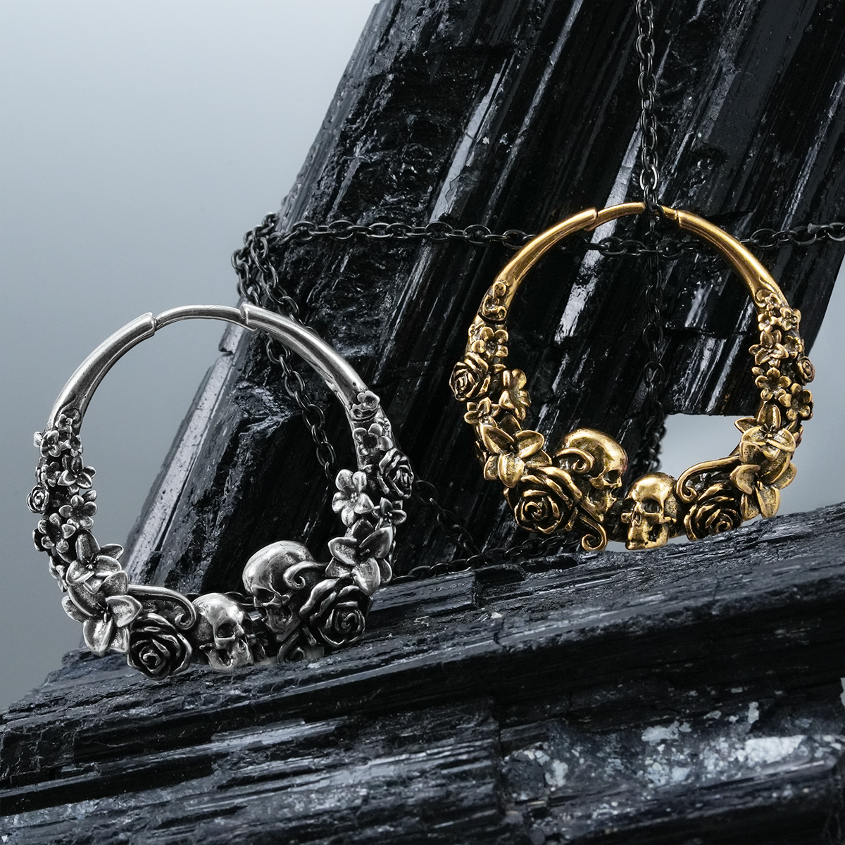 Silver and gold Skull Blossom hoop earrings displayed on black crystals