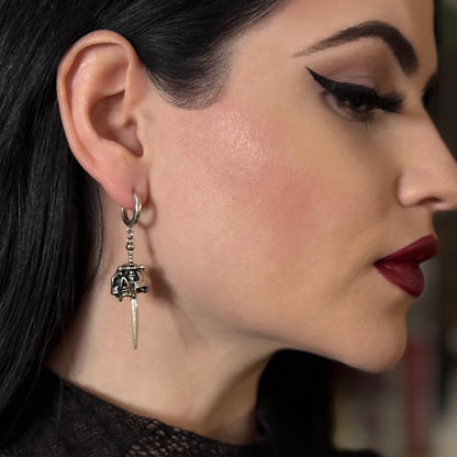 Model wearing a silver Skull Dagger hoop earring with long blade drop