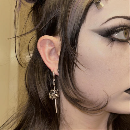 Model wearing a silver Skull Dagger hoop earring with skull and blade pendant