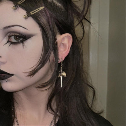 Model wearing a silver Skull Dagger earring with long pointed drop