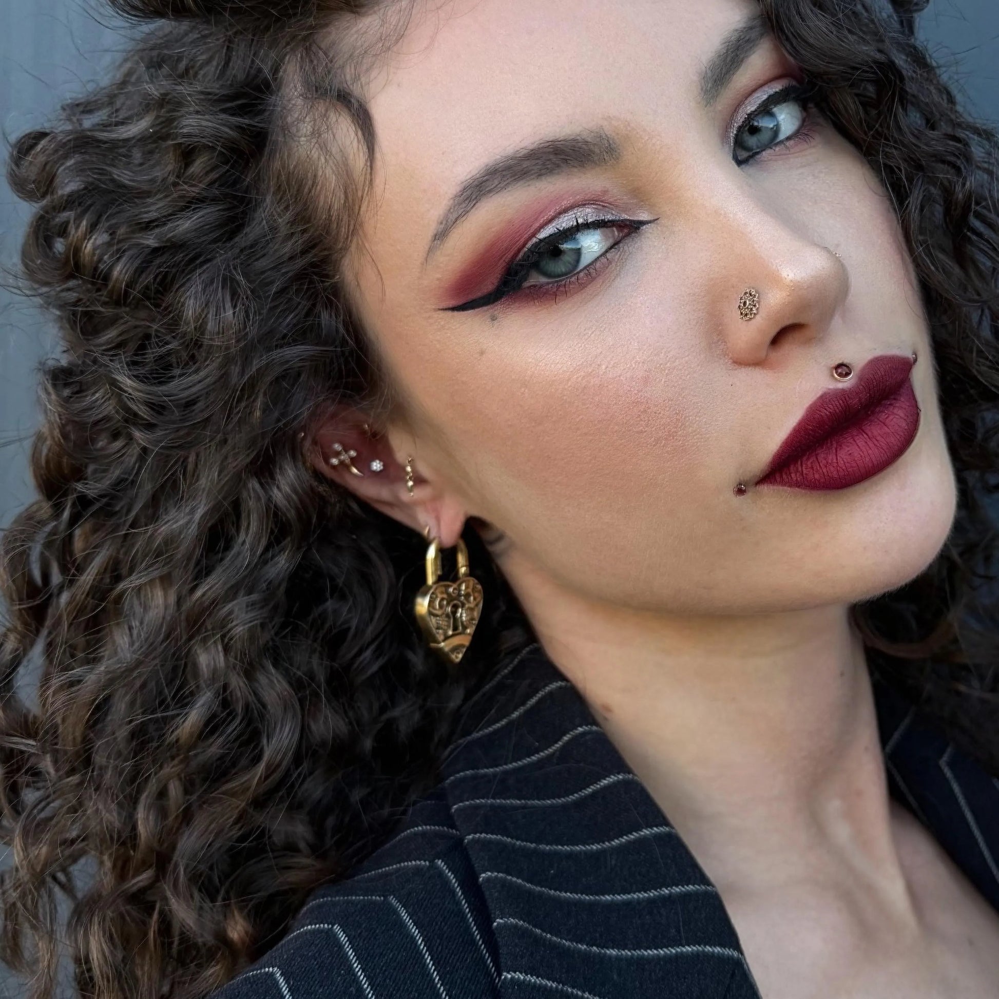 Model wearing gold Skull Heartlock Earrings with gothic heart lock and skull engraving design