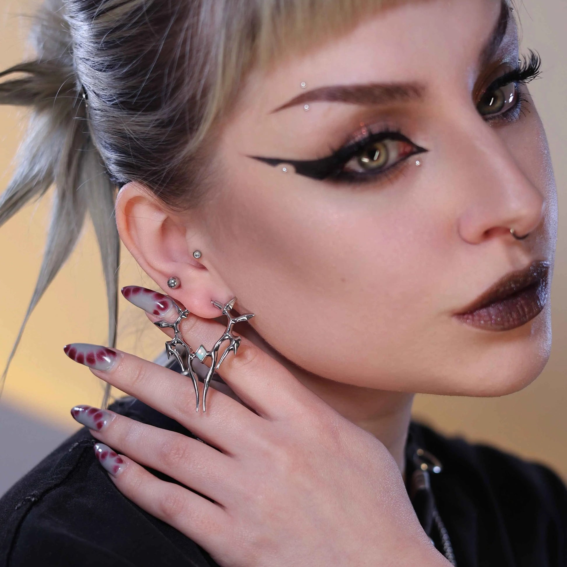 solar guardian earrings worn by model in a close-up portrait, showcasing the sharp symmetrical silver earring design