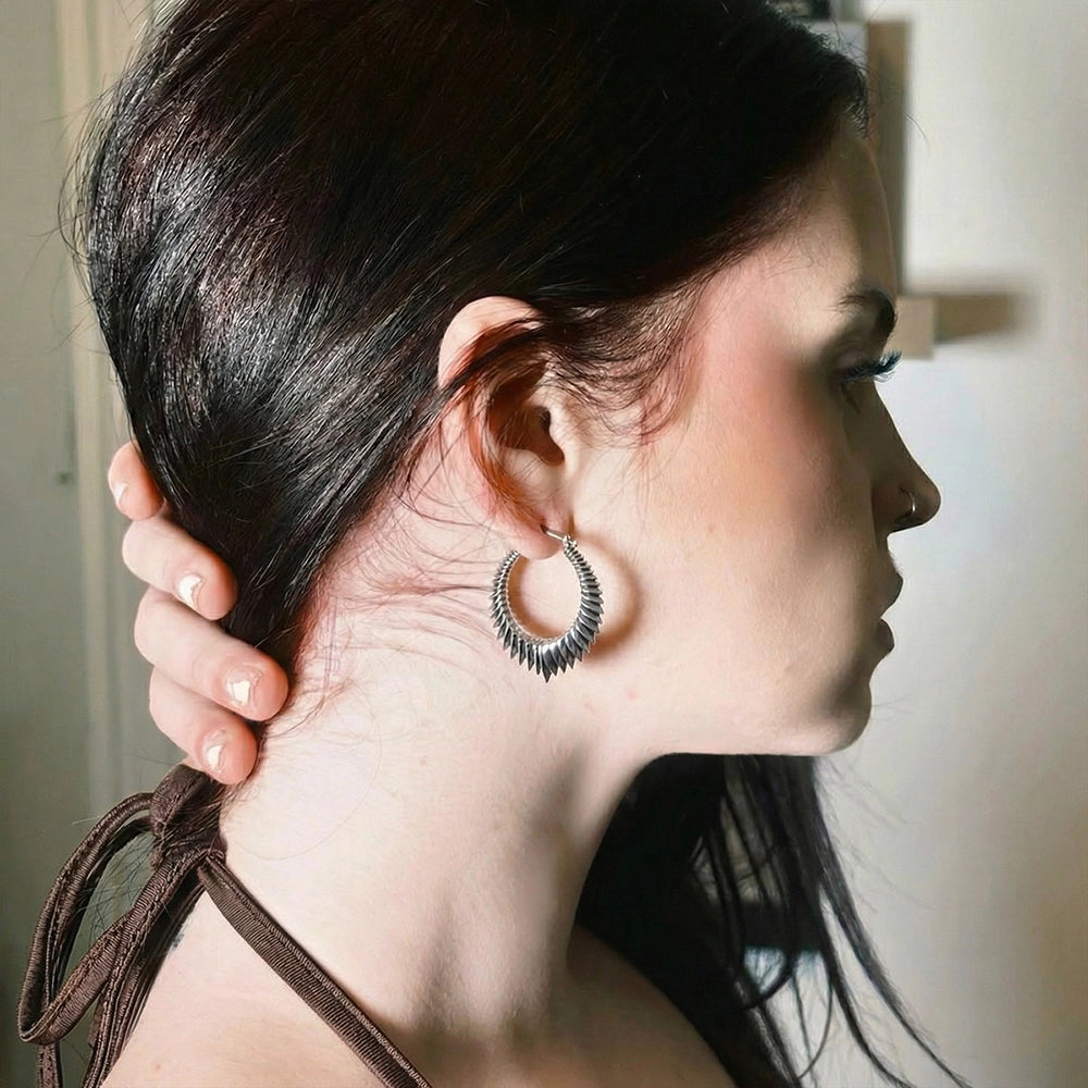 Side profile of a person wearing an oxidized silver-tone spine hoop earring