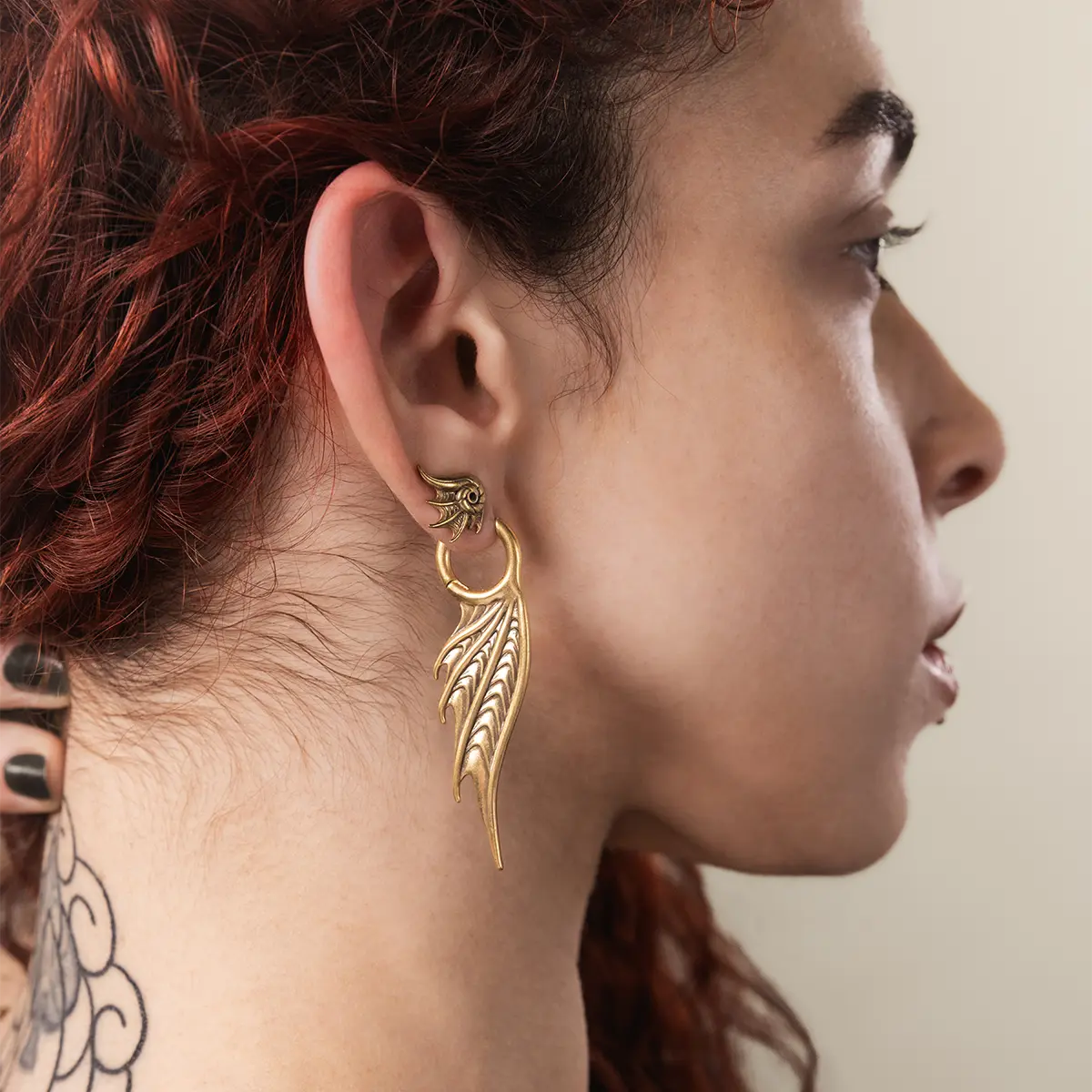 Side view of a model wearing the gold Spined Wing Earrings, showing the sharp vertical drop and coastal gothic styling.