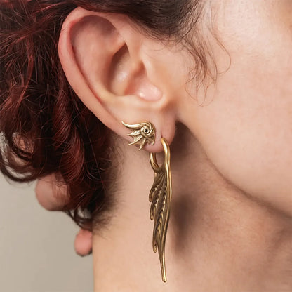 Model wearing Spined Wing Earrings featuring elongated ribbed wing-shaped drops suspended from hoops, creating a sharp vertical silhouette inspired by siren wings, coastal darkness, and gothic organic forms.