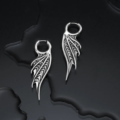 Silver Spined Wing Earrings displayed on a dark wet surface, highlighting the sharp ribbed wing shape and sea-worn gothic silhouette.