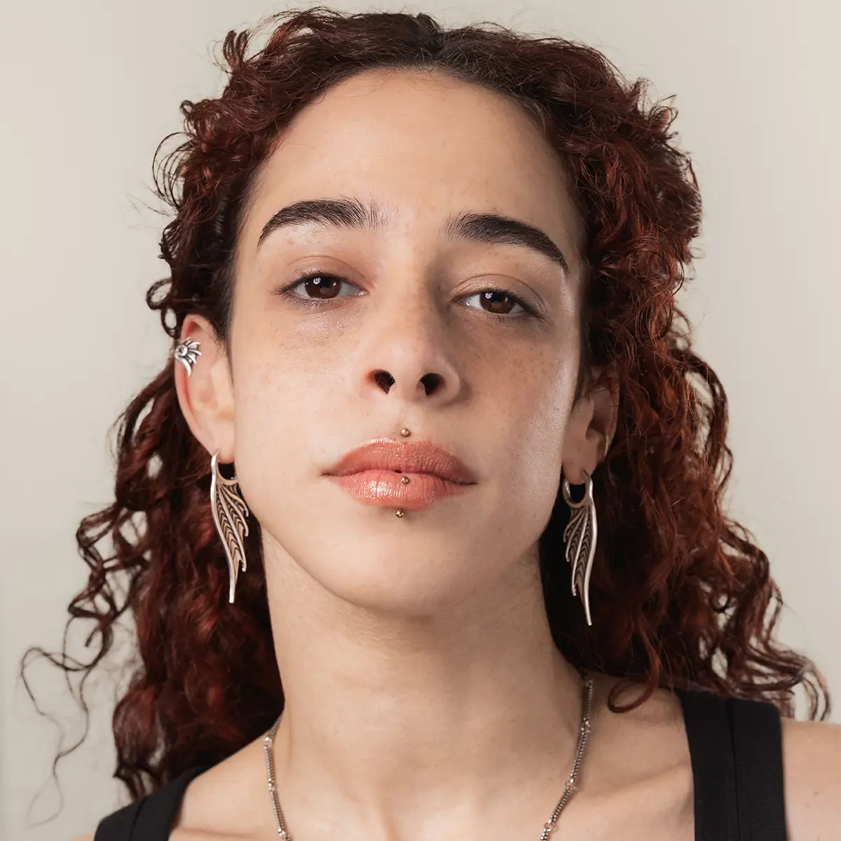 Model wearing the silver Spined Wing Earrings with a narrow vertical silhouette and sculptural siren-wing design.