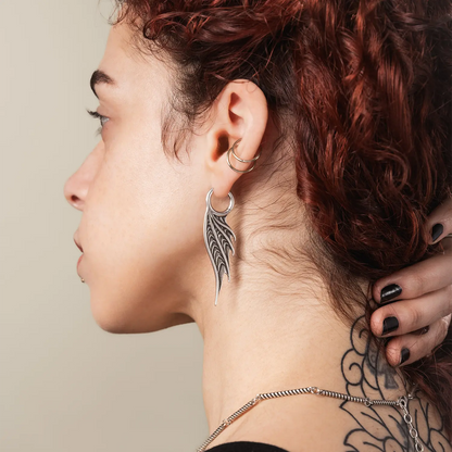 Model wearing the silver Spined Wing Earrings, showing the long ribbed wing drop silhouette and dark ocean-inspired styling.