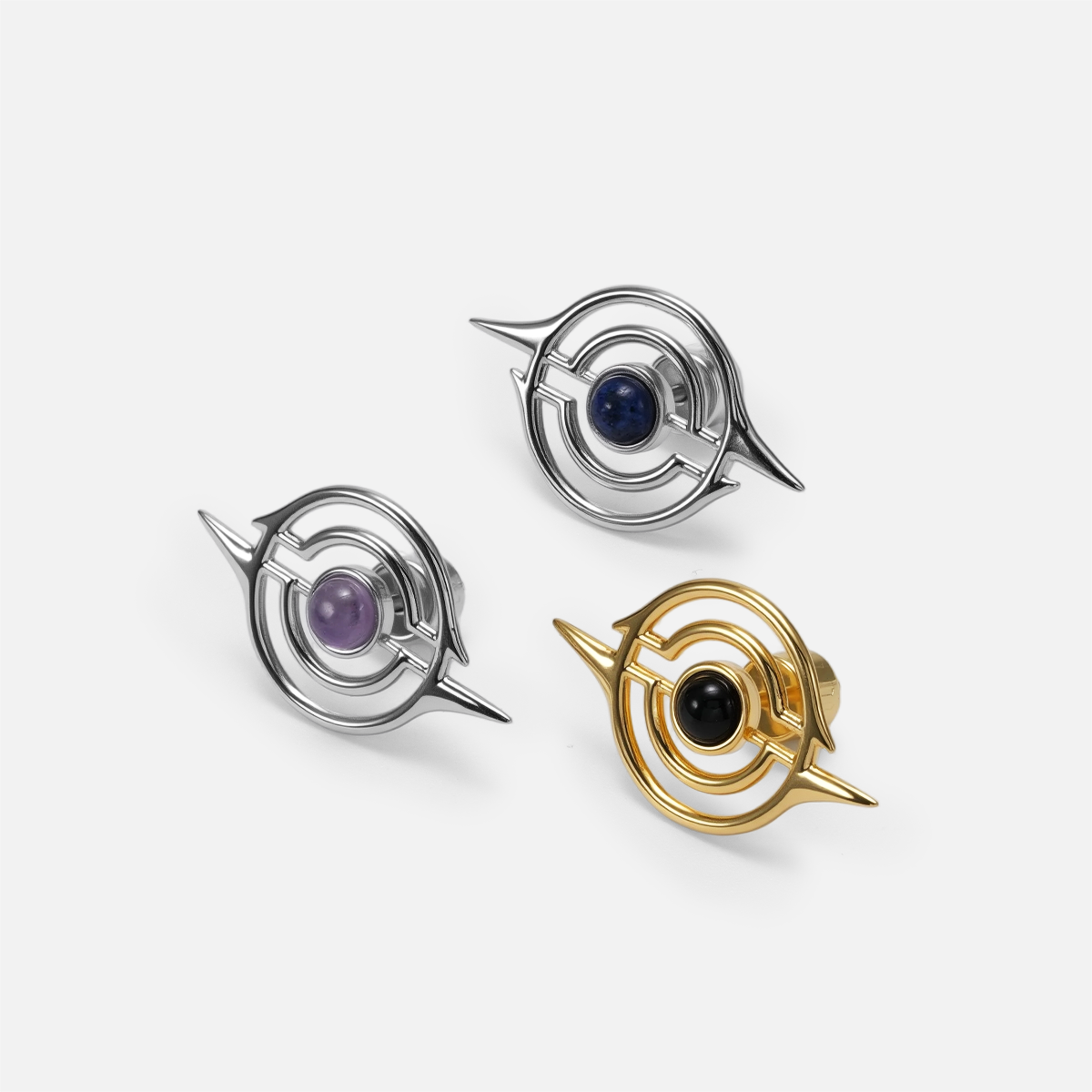 Three ear studs with concentric ring design in silver-tone and gold-tone, featuring blue, purple, and black stone centers