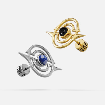 Silver-tone and gold-tone ear studs with concentric ring design, blue and black stone centers, floating angled view