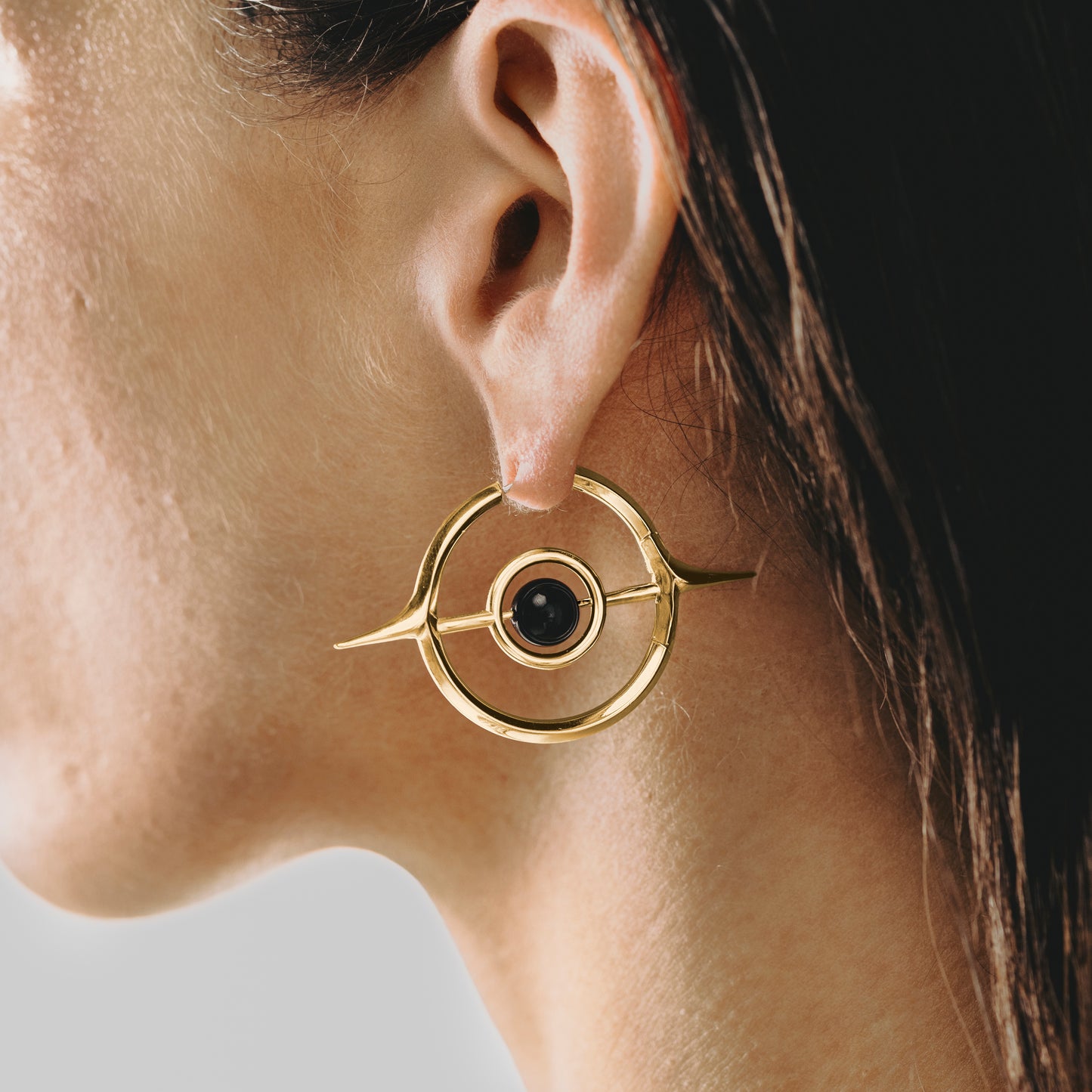 Close-up of gold Stellar Grace hoop earring with black center accent