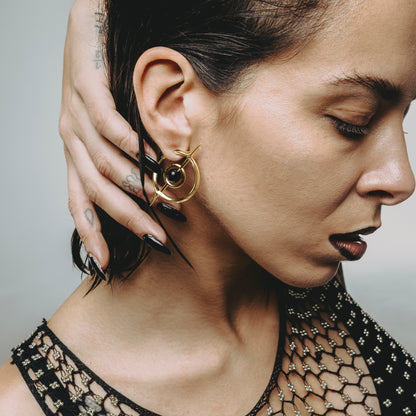 Model wearing a gold Stellar Grace hoop earring with circular orbit design
