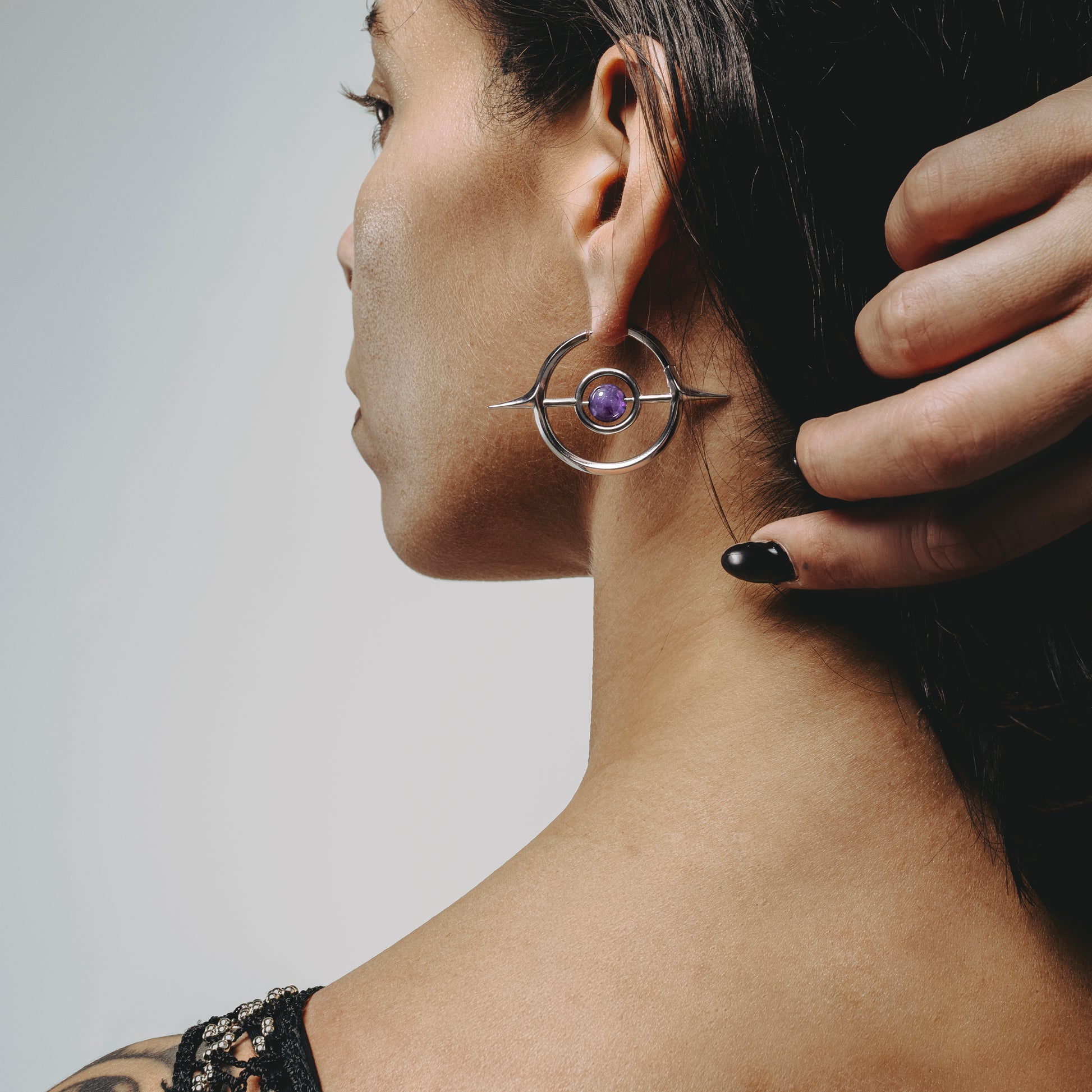 Rear side view of model wearing a silver Stellar Grace hoop earring with purple center