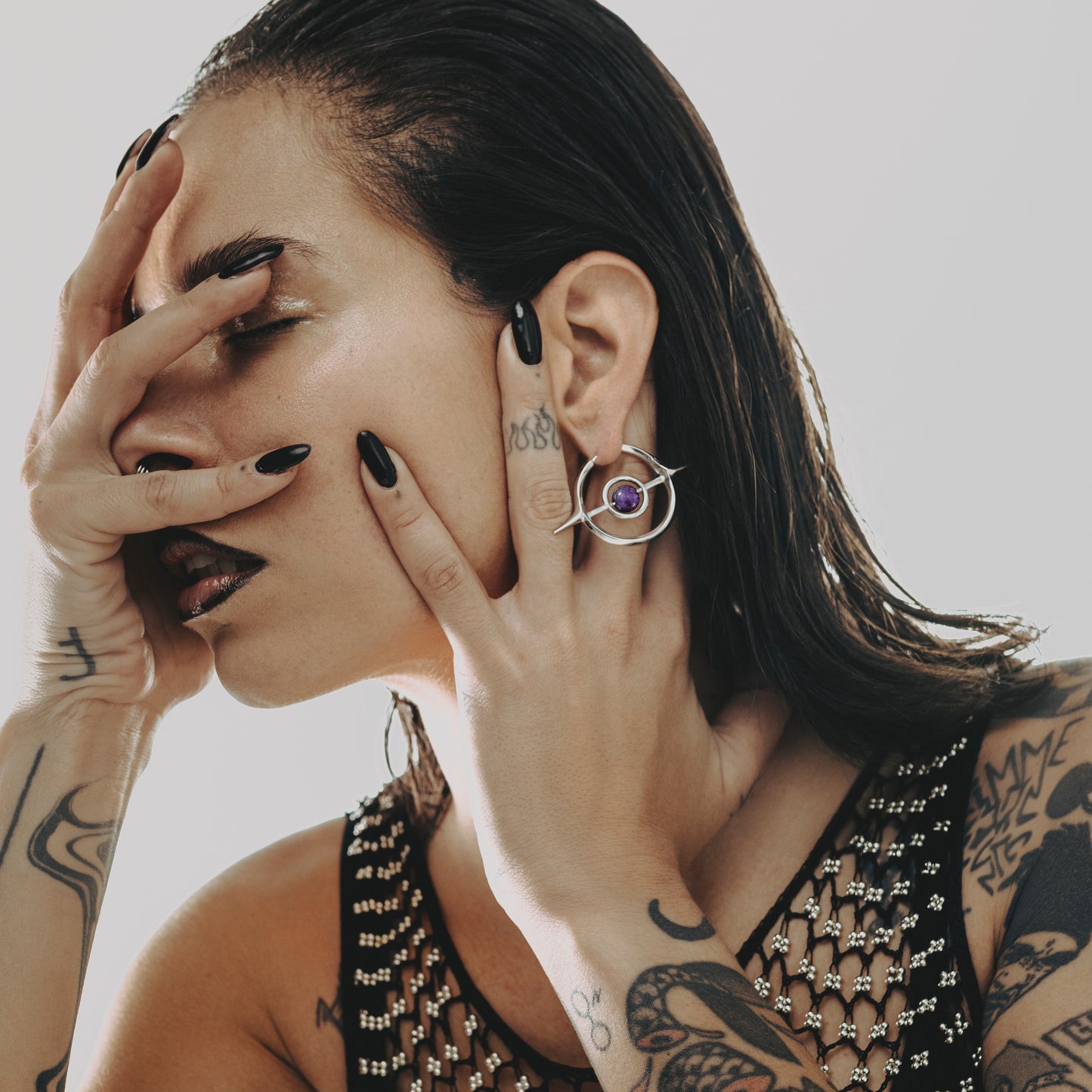 Model wearing a silver Stellar Grace hoop earring with purple center accent