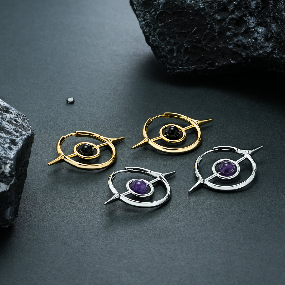 Two pairs of gold and silver Stellar Grace hoop earrings on black stone