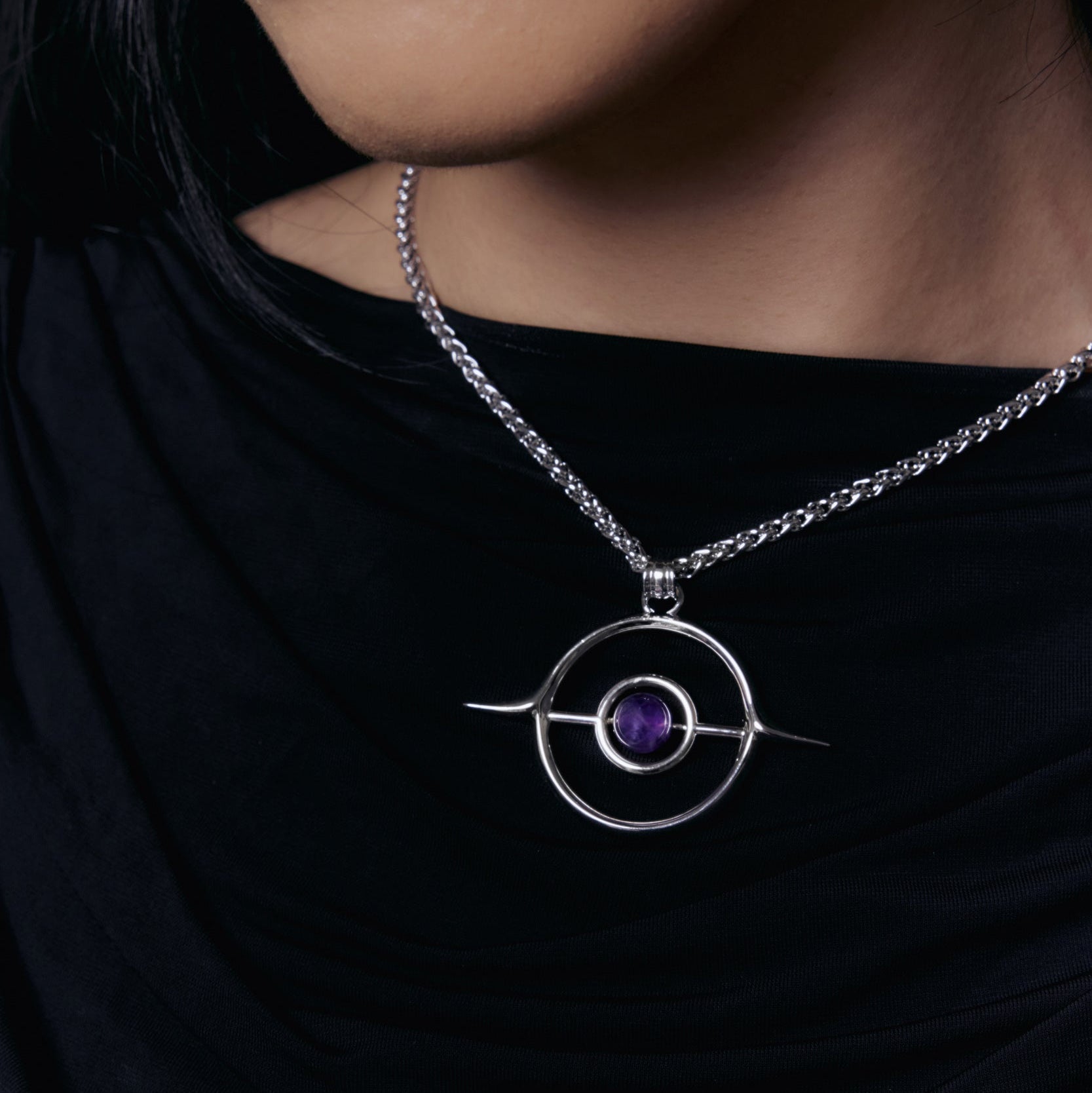 Stellar Grace Necklace worn on a model, showing the open circle pendant with a purple stone against a black top
