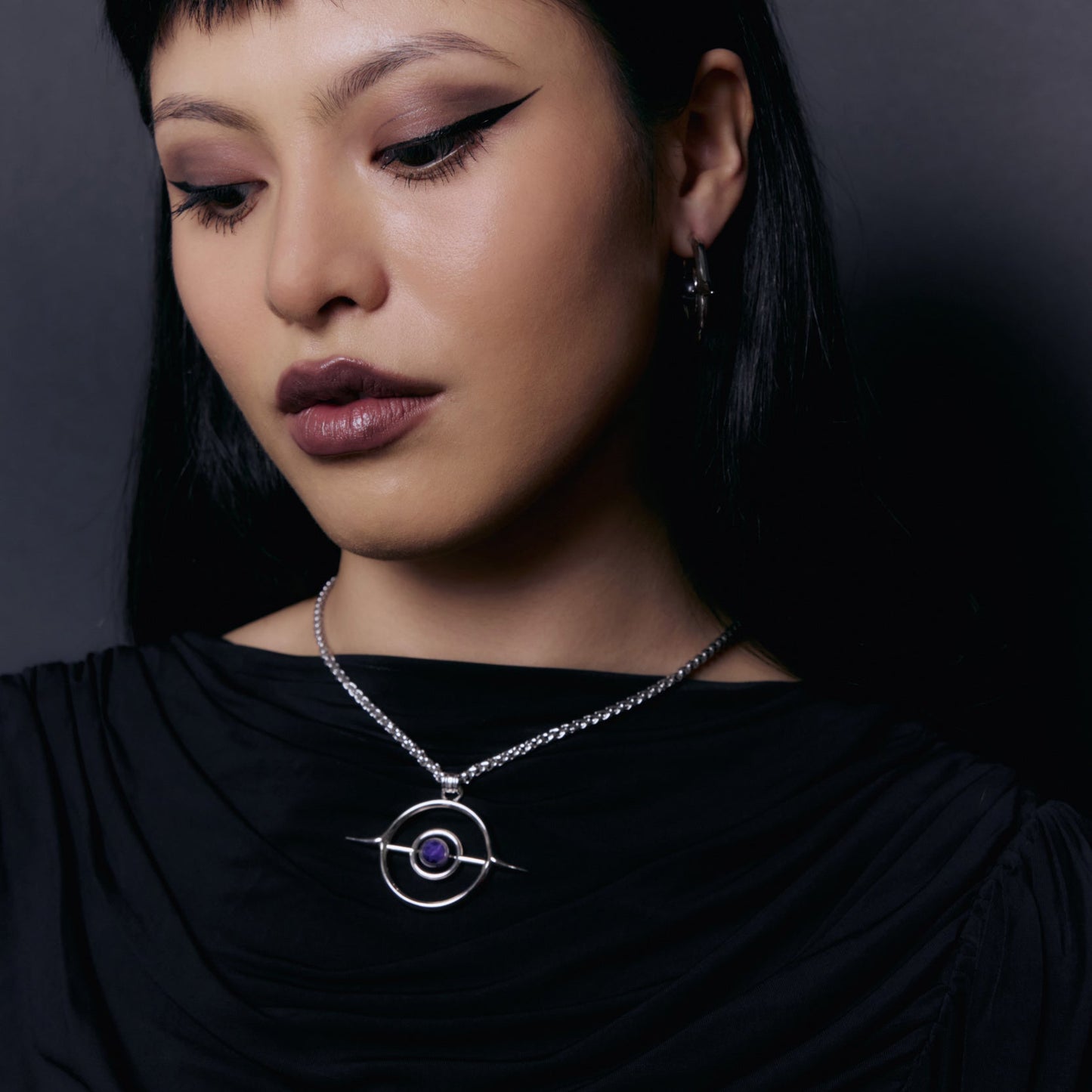 Model wearing a silver Stellar Grace necklace with purple center pendant