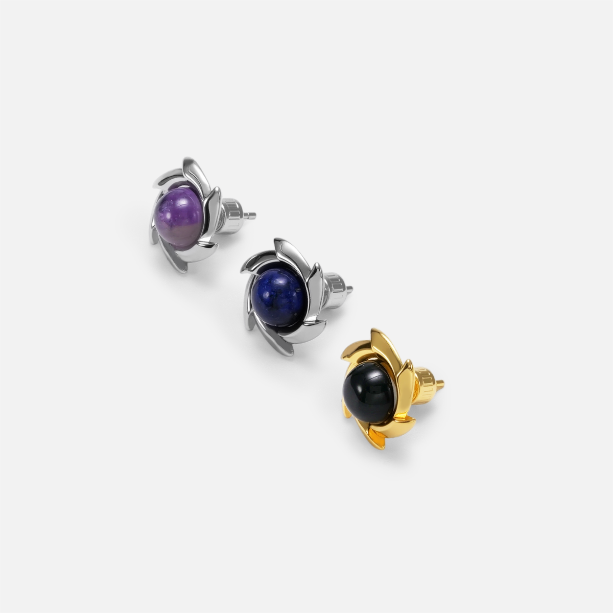 Three pinwheel stud earrings arranged diagonally with purple, blue, and black stones in silver-tone and gold-tone tones