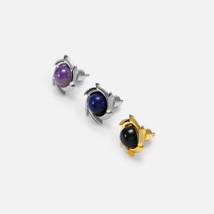 Three pinwheel stud earrings arranged diagonally with purple, blue, and black stones in silver-tone and gold-tone tones