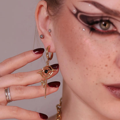 Model wearing the gold Stellar Path Earrings with black obsidian center, orbital metal lines, pointed star drop, and celestial gothic styling.