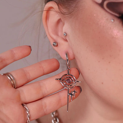 Model wearing the silver Stellar Path Earrings with amethyst center, orbital frame, pointed star drop, and celestial-inspired gothic styling.
