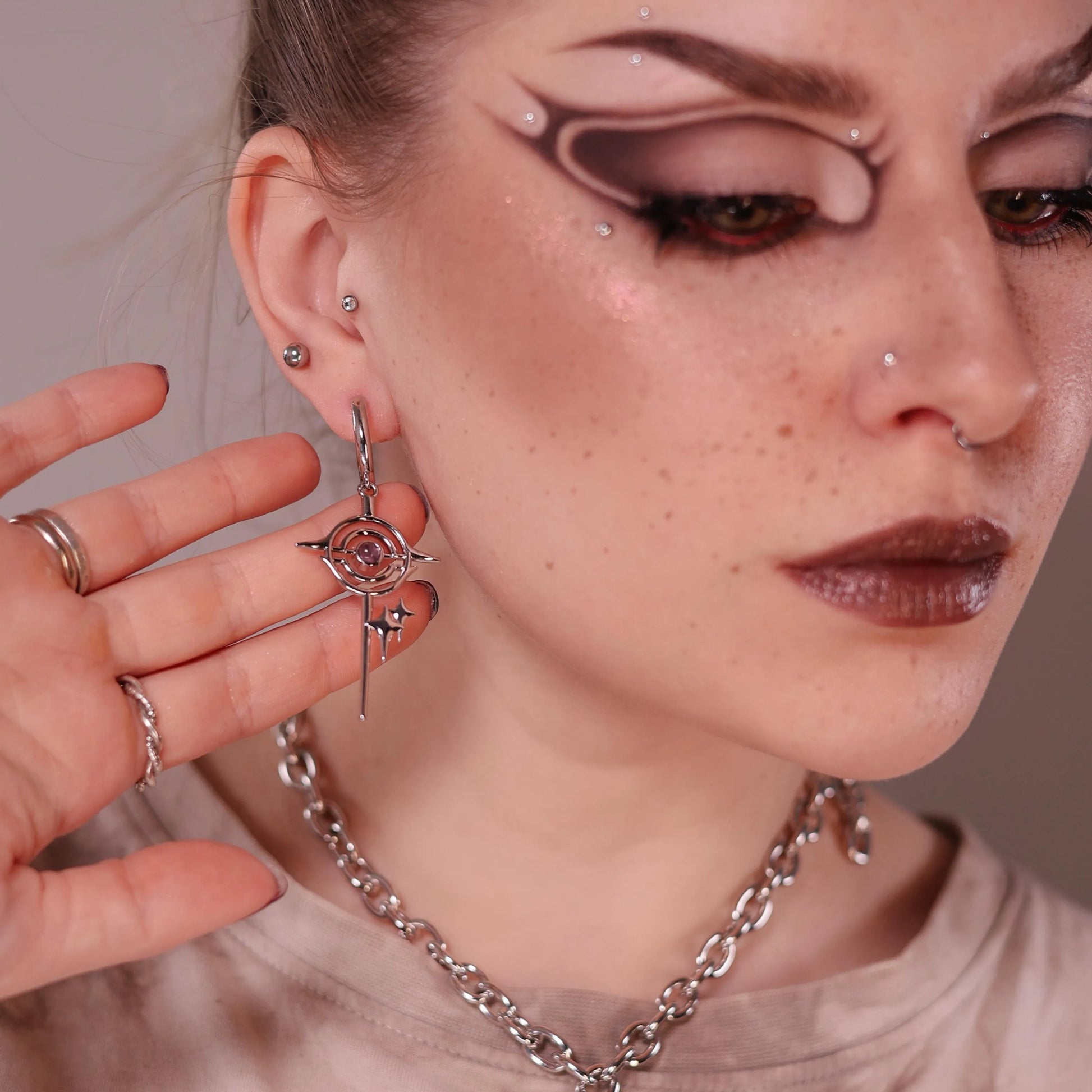 Model wearing the silver Stellar Path Earrings with black obsidian center, star drop silhouette, orbital metal lines, and dark celestial gothic styling.