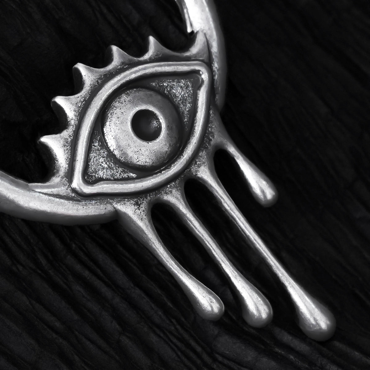 Close-up of silver Surrealist Eye earring with eye and dripping details