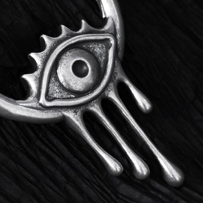 Close-up of silver Surrealist Eye earring with eye and dripping details