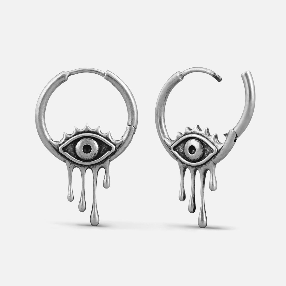 Silver-tone hoop earrings featuring a weeping eye motif with dripping tear details, shown open and closed