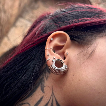 Close-up of silver Symmetrical Radiance tunnel worn with multiple ear piercings