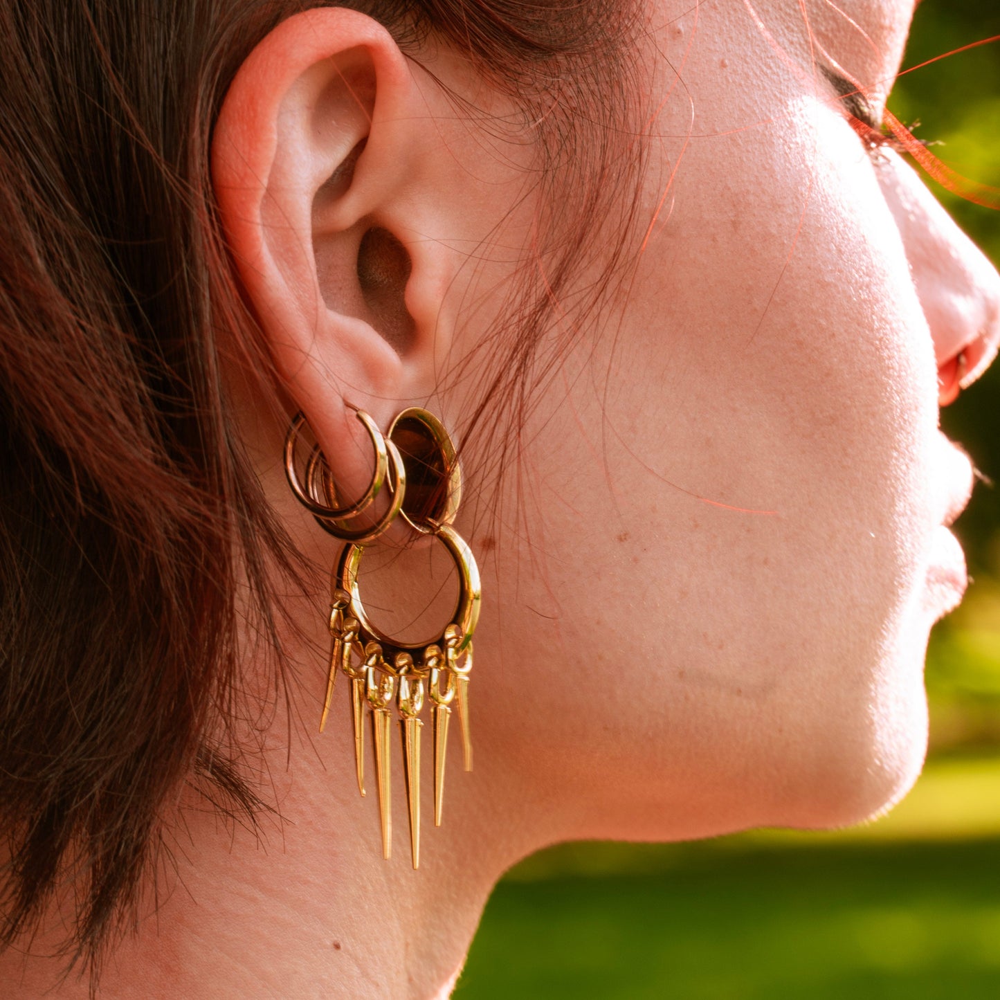 Gold-tone Tapered Chic hoop earring worn in side profile, with layered ear hoops above it