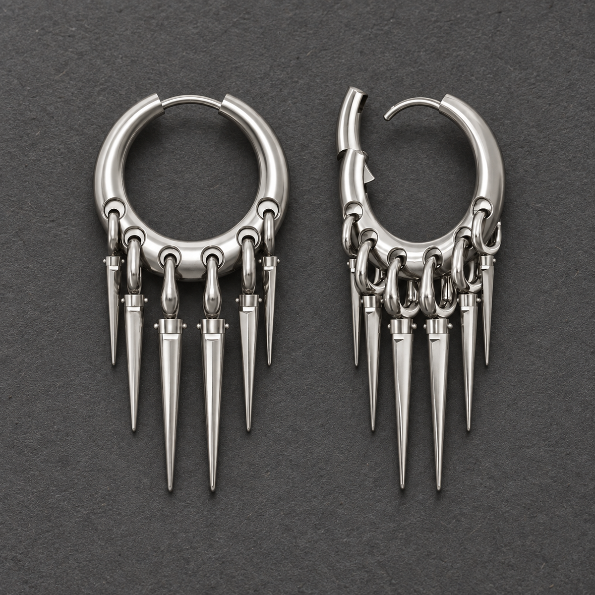 Pair of silver-tone Tapered Chic hoop earrings with graduated spike drops on a textured gray surface.