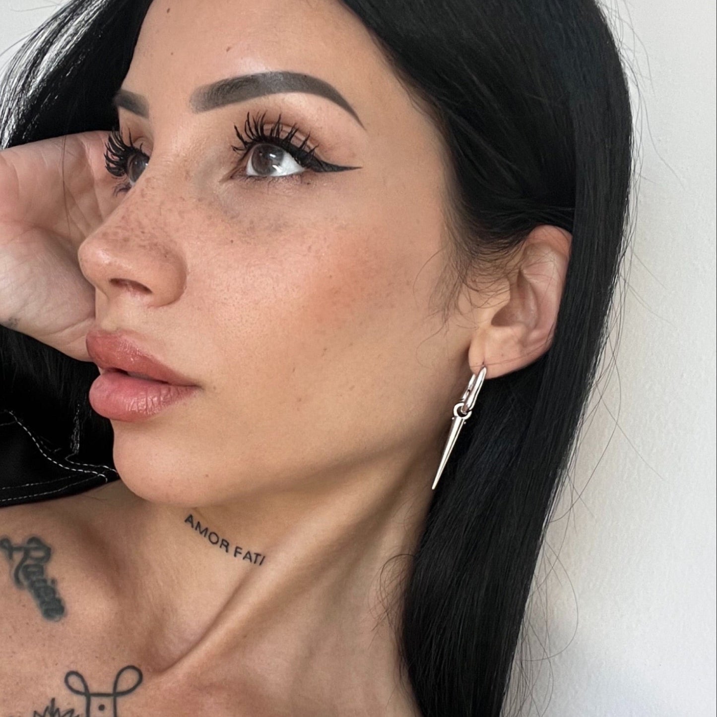 Silver-tone tapered edge earring on a hoop, worn by a model shown in close-up side profile