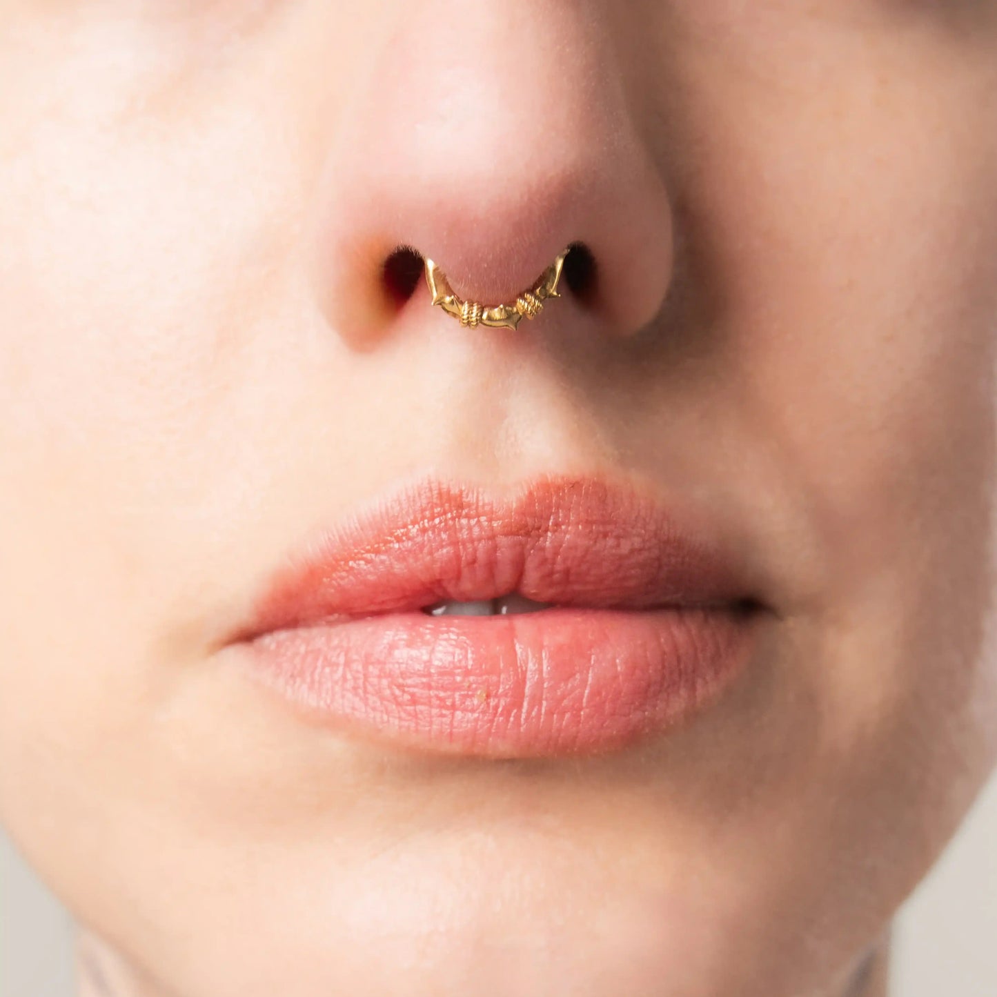 Close-up of gold Thorn Bramble Clicker worn as a septum ring with thorn details