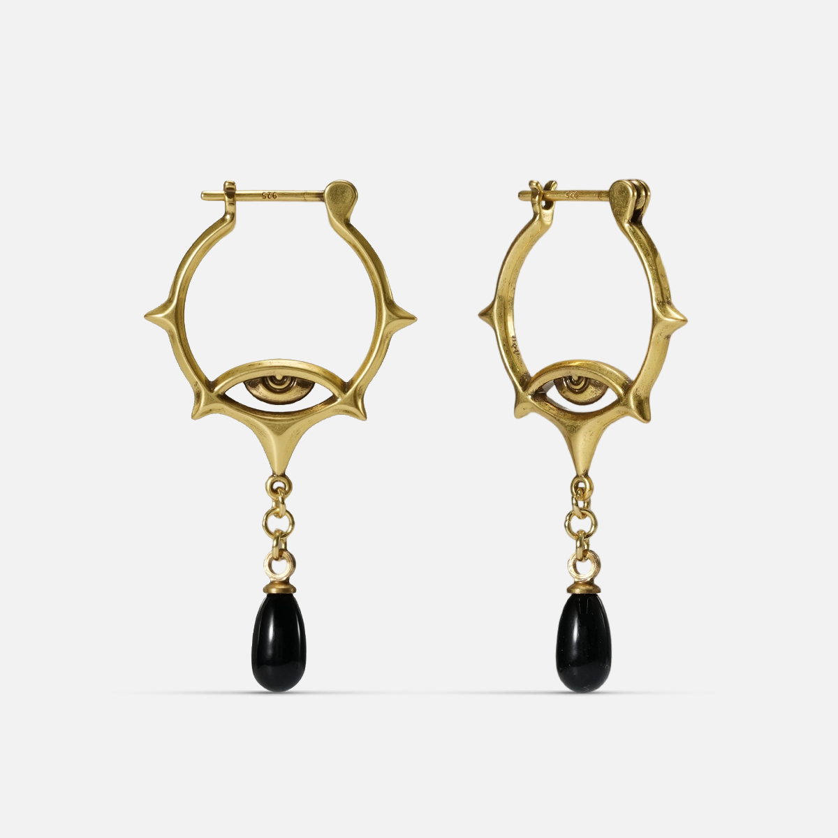 Gold-tone Thorned Gaze Hoop Earrings shown from the front with engraved eye motifs and suspended black teardrop accents.