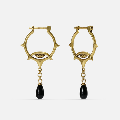 Gold-tone Thorned Gaze Hoop Earrings shown from the front with engraved eye motifs and suspended black teardrop accents.