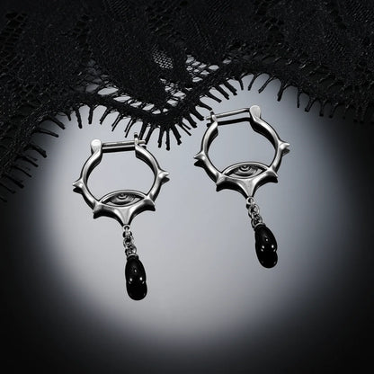 Antiqued silver-tone Thorned Gaze Hoop Earrings displayed as a pair against black lace on a dark reflective surface.