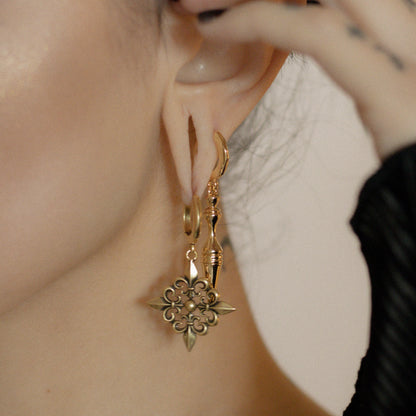 Close-up of gold Timeless Spear earring worn with a floral hoop earring