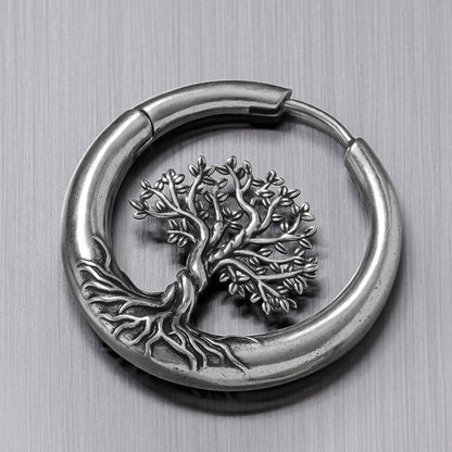 Close-up of a silver-tone hoop earring with detailed tree of life and roots design