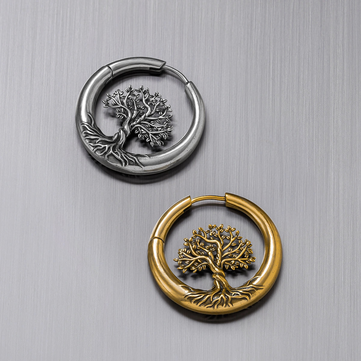 Silver-tone and gold-tone tree of life hoop earrings laid flat side by side
