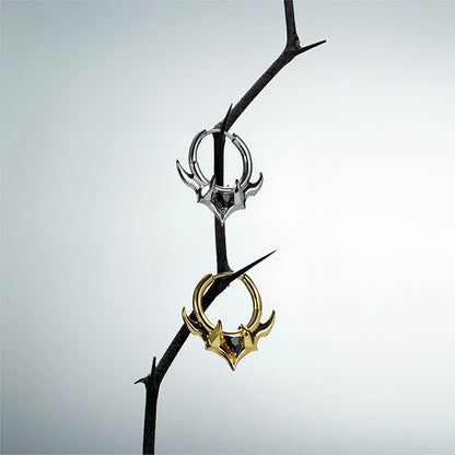 Silver and gold Trident Crest stone hoop earrings hanging from a dark branch