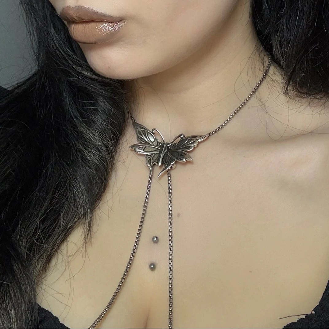 twilight moth necklace shown on a model, featuring a butterfly-moth centerpiece with long cascading chain drops in a close-up styling shot